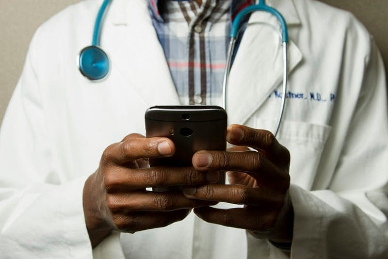 A healthcare worker in a clinical setting using a device — representing KelinaCare's patient-facing healthcare web application.
